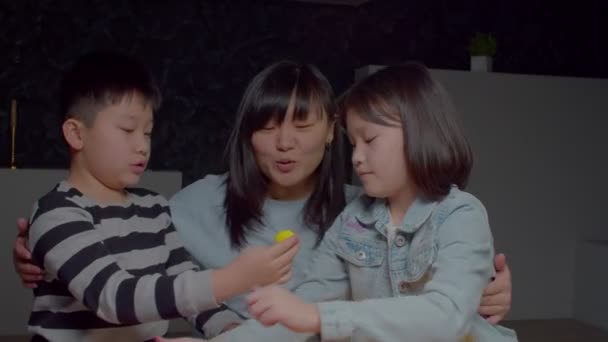 充满爱心的漂亮的亚洲母亲 在用五颜六色的玩具打造家庭玩具的同时 拥抱着快乐的青春期前兄弟姐妹 表达爱 关心和坚强的联系 — 图库视频影像