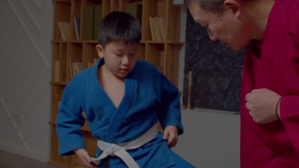 積極的に決定された愛らしい青年アジアのTaekwondo学生の肖像シニアマスター練習武道と一致して 屋内スポーツトレーニング中にキック技術を学ぶ — ストック動画