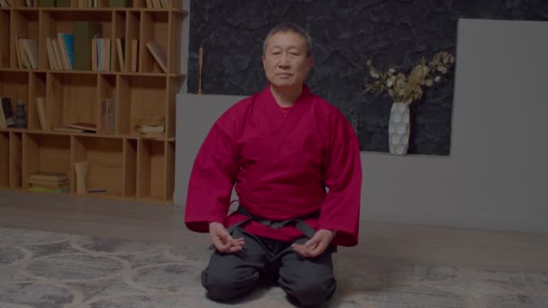 男子武术高级大师安静地坐在地板上跪着 手握泥巴手势和冥想 舒缓室内压力 放松精神 — 图库视频影像