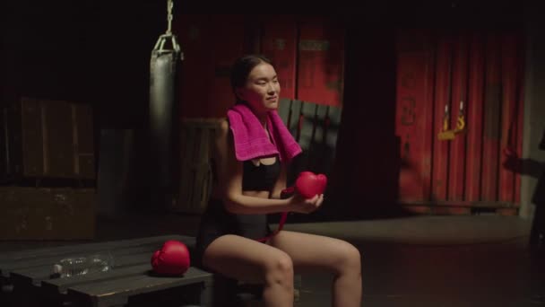 스포츠에 아시아 선수가 팔레트에 체육관에서 훈련을 닦으며 글러브를 수건으로 닦는다 — 비디오