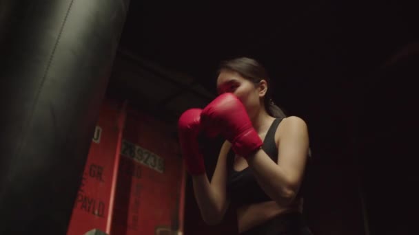 在拳击训练的手套训练中 设计并改进了带冲刺袋的刺拳和上勾拳技术 展示了决心积极运动的适合漂亮的亚洲女子拳击运动员的形象 在Grunge体育馆 — 图库视频影像
