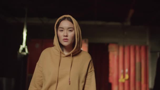 스타일 매력적 아시아 소녀가 어두운 환경에서 시선으로 후드를 위험성을 — 비디오