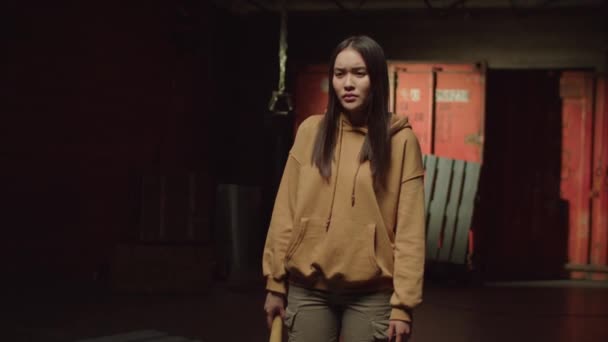 在黑暗的工业环境中 穿着球拍的粗野迷人的亚洲女流氓表现出恼怒 敌意和恶劣的态度 — 图库视频影像