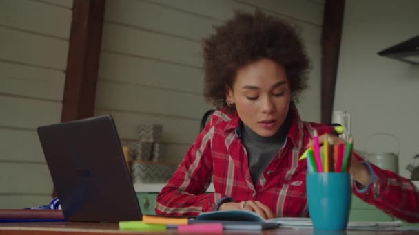 聪明漂亮的非洲裔美国女大学生在笔记本电脑上写大学作文时 要用记号笔突出课本中的要点 为考试做准备 — 图库视频影像