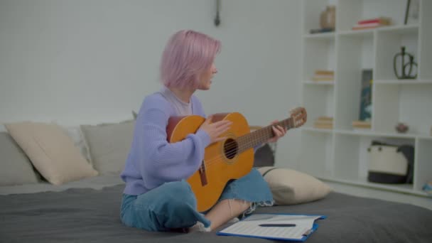 Joyful Atraente Rosa Cabelo Jovem Músico Feminino Sentado Cama Tocando — Vídeo de Stock