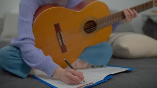 기사보기 재능있는 작곡가가 어쿠스틱 기타로 연주하는 새로운 작곡하고 악보를 실내에서 — 비디오