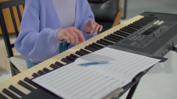 才华横溢的女作曲家在室内创作新歌的同时 在室内演奏电子合成器 创作音乐 并将音乐笔记写入乐谱 — 图库视频影像