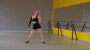 Zarif, motive edici, pembe saçlı, aktif giyimli, serbest dans eğitimi veren, dans ederken bileğini burkan, stüdyoda acı veren ifadeyle bacağına dokunan çekici bir kadın dansçı..