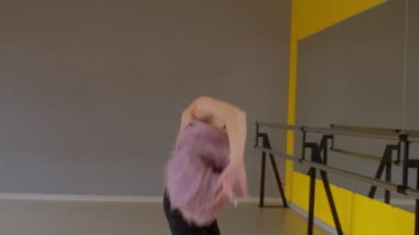 Zarif, çekici, zayıf, formda, aynanın önünde duran, ısınma egzersizleri yapan, kol ve sırt kaslarını esneten, dans stüdyosunda prova yapmak için vücudu hazırlayan bir kadın..