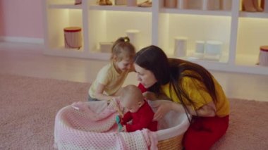 Neşeli, pozitif, çekici anne ve sevimli, mutlu, anaokulu çağındaki kız çocuğunun portresi, sepetin içinde oturan, sıcak duyguları, sevgiyi ve bakımı ifade ediyor. .