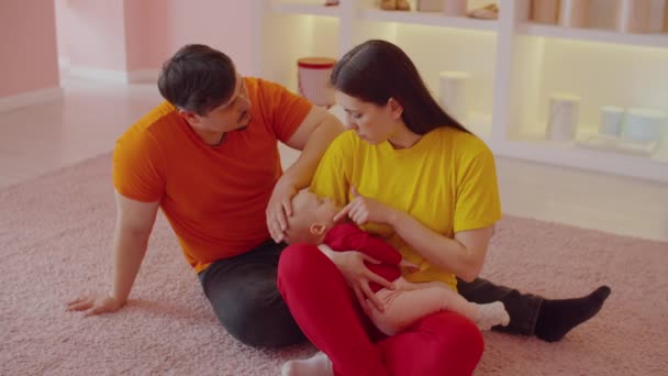 Люблячі Привабливі Батьки Сидять Підлозі Тримаючи Сплячу Чарівну Немовлячу Дівчинку — стокове відео