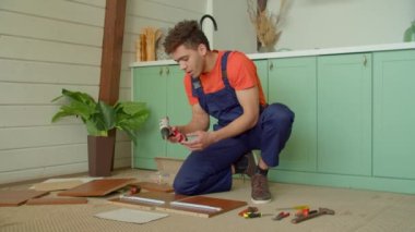 Koruyucu iş giyiminde yetenekli Afrikalı Amerikalı tamirci DIY mobilya montajı, çekmece slaytları montajı ve kablosuz elektrikli tornavida kullanarak vidaları sıkma.