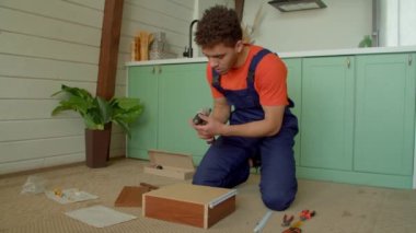 Becerikli Afrikalı Amerikalı tamirci kendini kapatma çekmecesi slaytı yerleştiriyor, elektrikli kablosuz matkap tornavidayı kullanarak vidaları sıkıyor ve DIY mobilyaları monte ediyor..