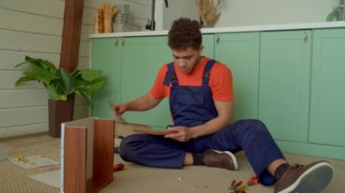 Koruyucu iş giysisinde yetenekli Afrikalı Amerikalı erkek boksör DIY mobilya montajı, komodindeki tahta pervazları çekiçle çekmeceye çivileme..