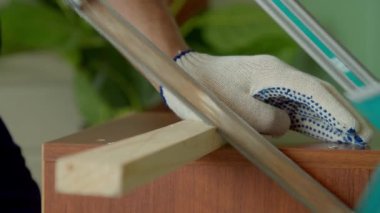 Koruyucu iş kıyafetleri ve eldivenler giyen, ahşap işçiliği yapan, el testeresiyle tahta kesen yetenekli siyah erkek boyanın yakın çekimi..