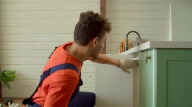 Çekici Afro-Amerikan tamircinin koruyucu iş elbisesi içinde mutfak dolabını tamir ederken, kablosuz elektrikli matkap tornavidayla vidaları sıkarken yan görüntüsü..
