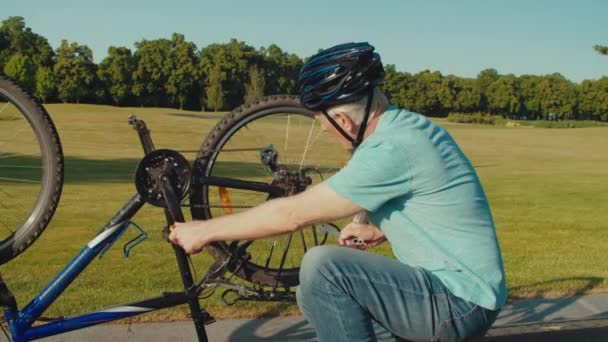 Active Senior Male Cyclist Bike Helmet Repairing Brake Transmission Rear — Stock Video