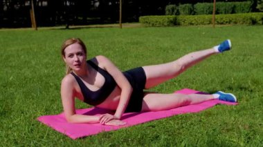 Aktif motivasyonlu çekici sportif orta yaşlı kadın yoga esneme egzersizi yapıyor, fitness paspası üzerinde yan bacak yükseltme egzersizi yapıyor, karın, bel ve kalça kaslarını güçlendiriyor..