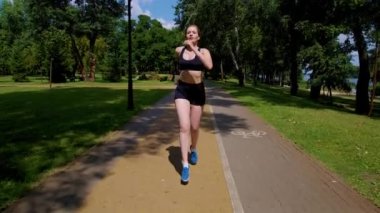 Güzel motive edilmiş orta yaşlı atletik kadın koşucu koşu antrenmanı yapıyor, dayanıklılığı ve kardiyovasküler zindeliği arttırıyor, park yolunda koşarken kasları güçlendiriyor..