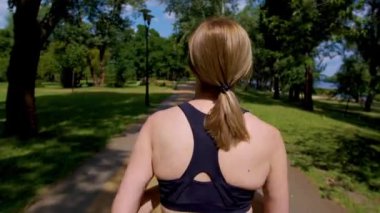 Aktif sağlıklı yaşam tarzının arka görünüşü belirlenmiş atletik formda kadın koşucu kardiyo antrenmanı yapıyor, yaz aylarında park yolunda koşarken güç ve dayanıklılık kazanıyor..