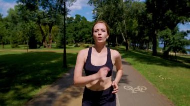 Yeşil parkta koşan çekici, orta yaşlı bir kadının portresi, kardiyovasküler uygunluğu artırıyor, motivasyon, adanmışlık ve spor eğitiminde kararlılık gösteriyor..
