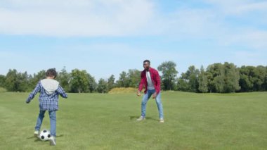 Pozitif yakışıklı siyah baba ve yeşil sahada oynarken futbol, antrenman ve futbol becerilerini gösteren sıradan giysili Afro-Amerikan çocuk.