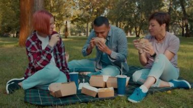 Neşeli, çekici, işitme engelli ebeveynler ve işitme kaybı yaşayan, birlikte vakit geçiren, işaret diliyle konuşan, piknik sırasında lezzetli hamburgerler yiyen neşeli, tatlı genç kız..