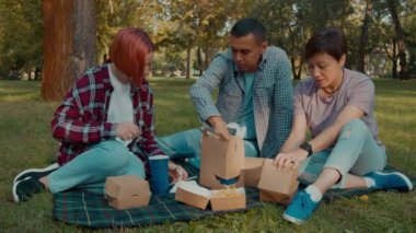İşitme engelli olumlu çekici ebeveynler ve işitme engelli tatlı bir kız çocuğu hafta sonu ve eğlencenin keyfini çıkarıyor, aile piknik yaparken fast food yiyor ve soda içiyor. Halk parkında
