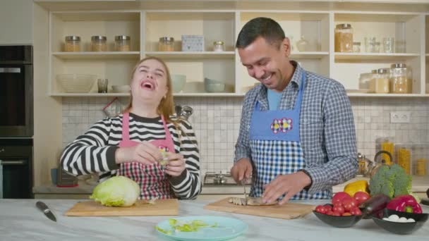 家庭用キッチンで調理しながら 新鮮なサラダの食材をチョッピングする シグナル言語を使用して話すエプロンを身に着けているハッピーな肯定的な魅力的な家族 — ストック動画