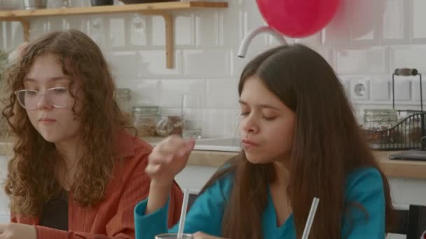 迷人的黑发少女的画像 眼睛闭着 咬着吃着美味的汉堡包 一边吃着美味的食物 一边和女性朋友一起在家里吃午饭 — 图库视频影像