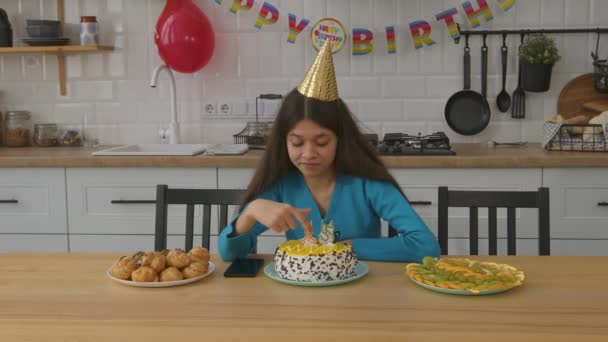 悲しい 魅力的な 十代の少女 深い考え パーティー帽子をかぶり お祝いのテーブルに座って 思春期について考え 自宅で誕生日を祝う間不確実性と心配を表現する — ストック動画