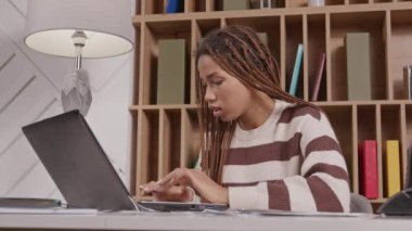 Güzel Afrikalı Amerikalı kadın girişimci çevrimiçi dizüstü bilgisayarla iletişim kuruyor. Yumruk pompasıyla yapılan başarılı anlaşmayı kutluyor. Evden uzaktan çalışırken heyecan, mutluluk ve neşe ifade ediyor..