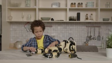 Becerikli, konsantre olmuş, akıllı, küçük çocuk, kırık oyuncakları tamir ediyor, iş aletlerini kullanıyor, fonksiyonlarını kontrol ediyor ve içeride zaman geçirirken hasarlı robotun özelliklerini kontrol ediyor..