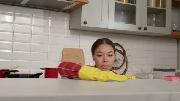 忙着集中注意力的黑人妇女的画像 她戴着防护手套做家务活 在厨房清理的时候用抹布擦拭和擦拭厨房台面的灰尘和油脂 — 图库视频影像