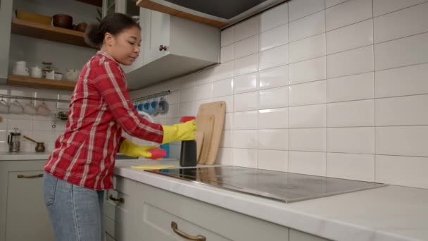 家事をする保護ゴム手袋の美しいアフリカ系アメリカ人女性 家庭用キッチンでスプレー洗剤とスポンジを使用してグリースから電気クックトップをクリーニング — ストック動画