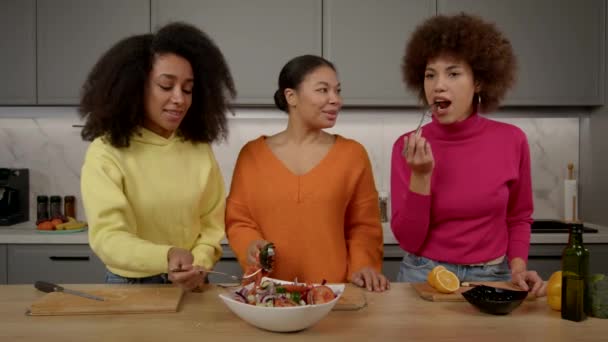 有吸引力的非洲裔美国妇女品尝新鲜美味的蔬菜沙拉 在享受休闲和在家庭厨房做饭的同时对美食感到满意 — 图库视频影像