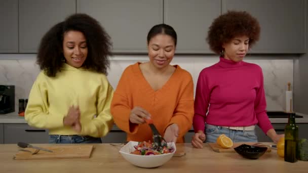 时尚美丽的黑人女人把新鲜的沙拉倒入碗中搅拌 禁止向不耐烦的女性朋友们品尝准备好的食物 也禁止在厨房里烹调时闻到美味的沙拉香味 — 图库视频影像