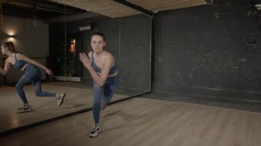 Spor kıyafetlerinde aktif motivasyona sahip çekici bir kadın idman yaparken hareket eder, kalça kaslarını güçlendirir ve iç kalça kaslarını çalıştırır..