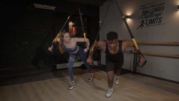 积极进取 有吸引力的运动健美女人和有决心的肌肉健美的非洲男人一起练习交叉训练 在健身房做俯卧撑锻炼 — 图库视频影像