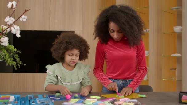 幸せな愛らしい幼少期の黒い娘とかわいい思いやりのある母親は 粘土をモデリングするカラフルな子供たちから手作りのおもちゃを作り 屋内で子供の創造性とスキルを開発します — ストック動画