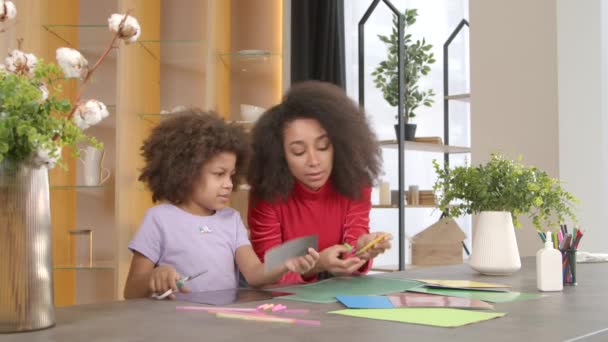 致力于可爱的学龄非洲裔美国女孩和积极迷人的黑人母亲 用彩纸手工制作礼物和贴画 在室内表达创造力和想象力 — 图库视频影像