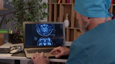 Bilgisayarlı bilgisayarda çalışan orta yaşlı erkek doktorların, hasta hastaların MRI beyin taramasını inceleyen, akşam muayenehanesinde teşhis ve hastalığın nedenini düşünen,.
