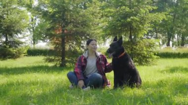 Rahat, orta yaşlı, Asyalı bir kadın tatlı, safkan, siyah bir köpeği okşuyor. Sevgi, ilgi ve beraberlik gösteriyor. Hem de boş vakitlerin tadını çıkarırken..