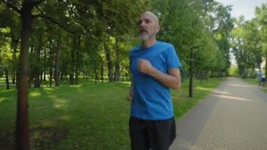 Aktif motivasyonlu atletik formda orta yaşlı erkek koşucu dizinden yaralanmış, dizkapağına masaj yapıyor, dışarıda koşu antrenmanı yaparken ağrıyı azaltmaya çalışıyor..