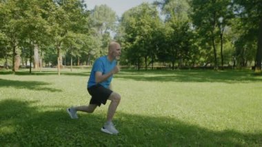 : Kararlı aktif sportif formda olgun bir adam plyometrik atlama egzersizleri yapıyor, kas gücünü ve kardiyovasküler sağlığını geliştiriyor ve parktaki yeşil alanda çalışıyor..