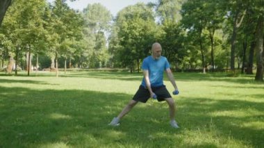 Aktif yaşam tarzını belirlemek spor kıyafetlerinde olgun bir adam olmak, çapraz antrenman yapmak, halterli yan hamleler yapmak, uyluk, kalça, kalça ve bacak kaslarını güçlendirmek.