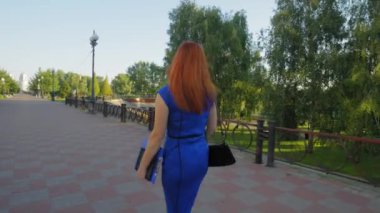 Kendine güvenen, orta yaşlı, çekici bir iş kadınının modaya uygun gündelik giysiler giyip sabah işe gitmek için şehir caddesinde yürümesi..