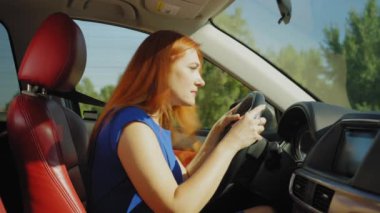 Şehir trafiğinde araba süren güzel kızıl saçlı kadın sürücünün yan görüntüsü, yolculuk sırasında motorlu taşıt kazası, kafa karışıklığını ve şoku gösteriyor..