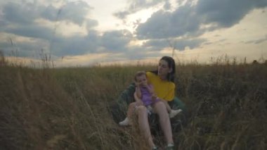 Sevecen anne puf mindere oturuyor kucağına tatlı bebek kızı sarılıyor yaz doğasında bağ kuruyor ve dinleniyor kırsal kesimdeki tatillerde mutluluk ve pozitifliği ifade ediyor.