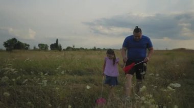 Olumlu yakışıklı baba ve güzel ilkokul kızı kelebek ağlarıyla çayırlarda yürüyor, böcekleri yakalıyor ve vahşi doğayı inceliyor aile ise kırsal kesimde eğleniyor.